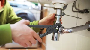 person tightening sink pipe